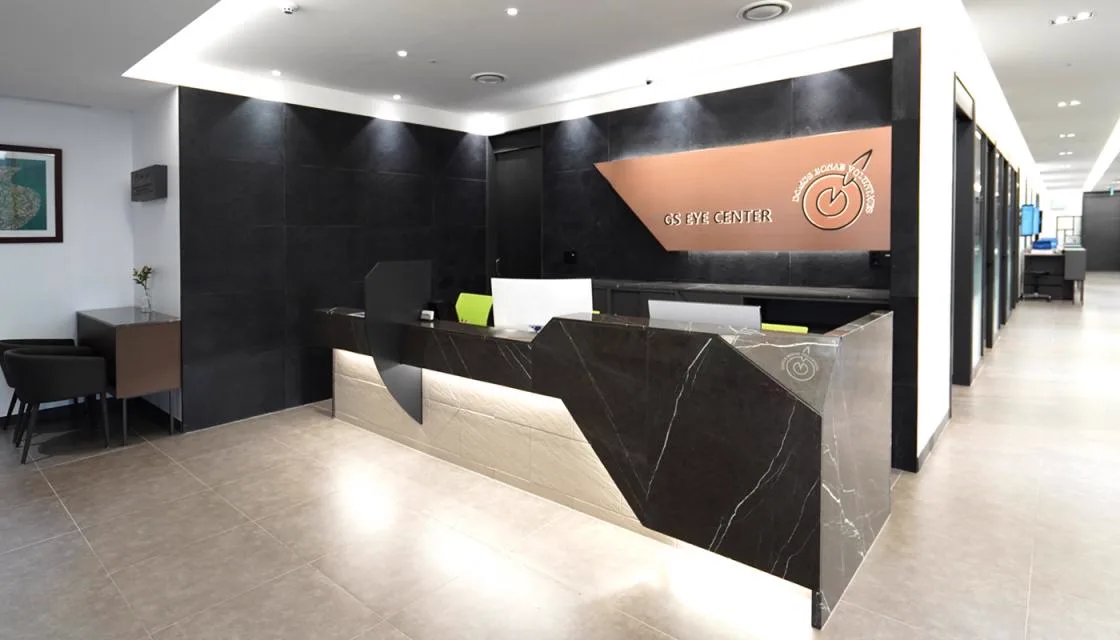 16F reception desk in dark stone with the GS Eye Center logo wall