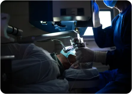 Surgeon operating under a surgical microscope in a darkened operating room