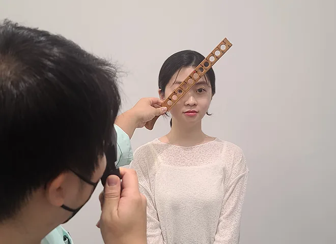 Examiner holding a lens rack in front of a patient during manual refraction testing